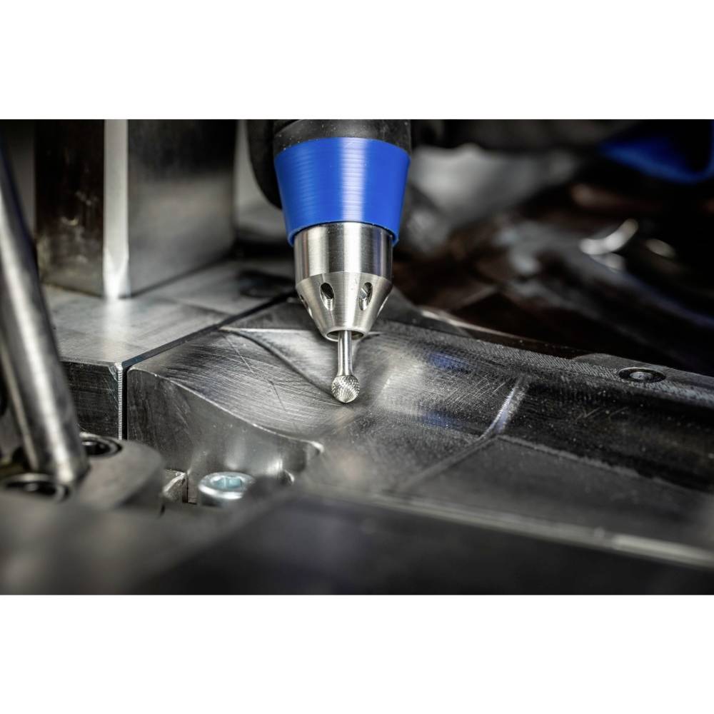 Frezarka CNC precyzyjnie obrabia powierzchnię metalową. Niebieiczny uchwyt zapewnia stabilność podczas frezowania złożonych elementów.