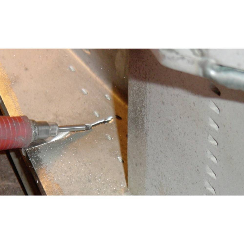 Zbliżenie wiertła, które wierci otwory w blasze metalowej. Podczas kontaktu wiertła z powierzchnią metalu lecą iskry.