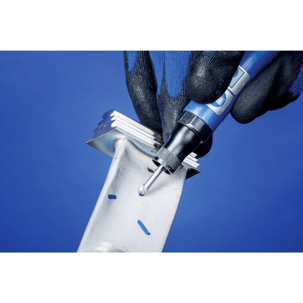 Dłoń w czarnej rękawicy trzyma niebieskie narzędzie i tnie lub kształtuje srebrny kawałek metalu na niebieskim tle.