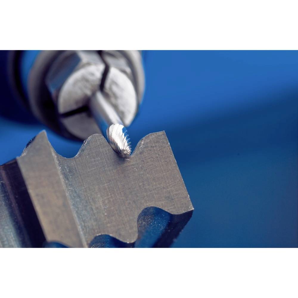 Zbliżenie frezarki obrabiającej kawałek metalu. Metal posiada postrzępione krawędzie, a tło jest rozmyte w odcieniach niebieskiego.