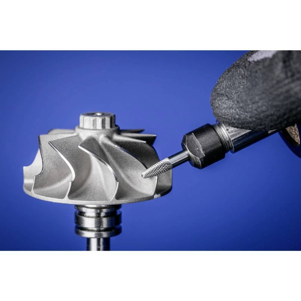 Metalowa frezarka precyzyjnie obrabia skomplikowaną część metalową. Na tle widoczny jest niebieski gradient.