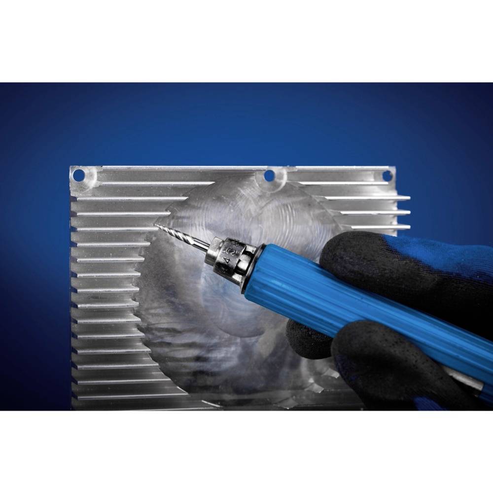 Dłoń w rękawicy trzyma niebieskie narzędzie przed blachą metalową z rowkami, prawdopodobnie do celów obróbki lub produkcji.