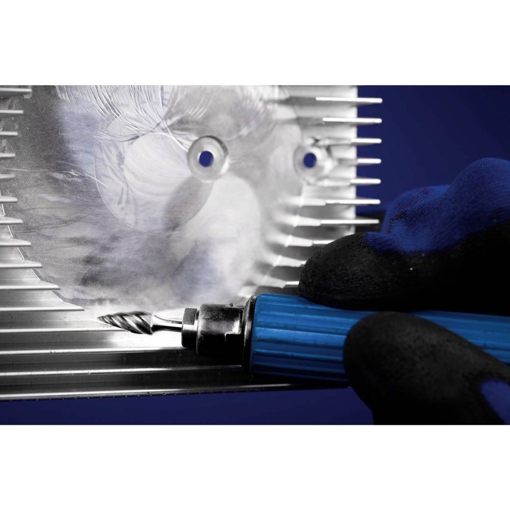 Rzeźbiarz rzeźbi twarz w metalu za pomocą grawerskiego narzędzia. Dłoń w rękawiczce pewnie trzyma narzędzie.