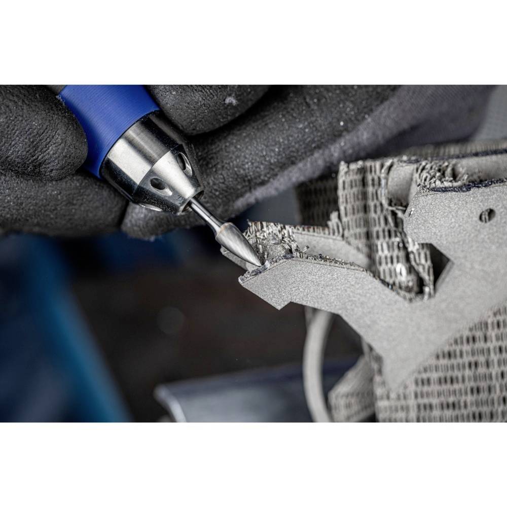 Rzemieślnik obrabia powierzchnię metalową za pomocą obrotowego narzędzia. Rękawice chronią dłonie podczas precyzyjnej pracy.