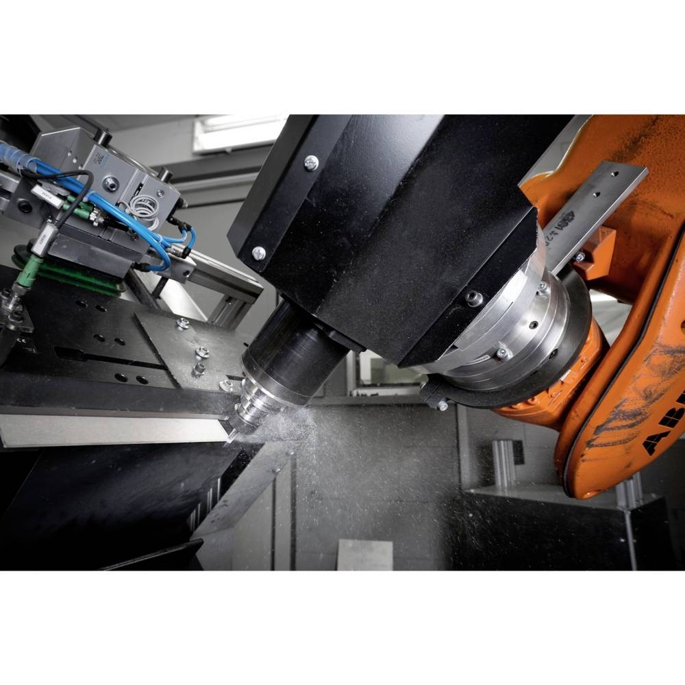 Przemysłowe ramię robota obrabia głowicą frezarską element metalowy. Widoczne są połączenia śrubowe i przewody. Scena przedstawia środowisko automatyzacji.