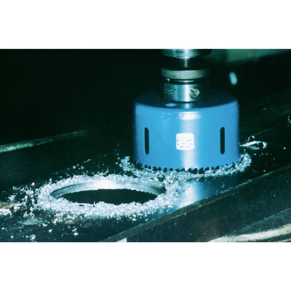 Niebieska piła tarczowa wycina okrągły otwór w arkuszu metalu, otoczony metalowymi wiórami.