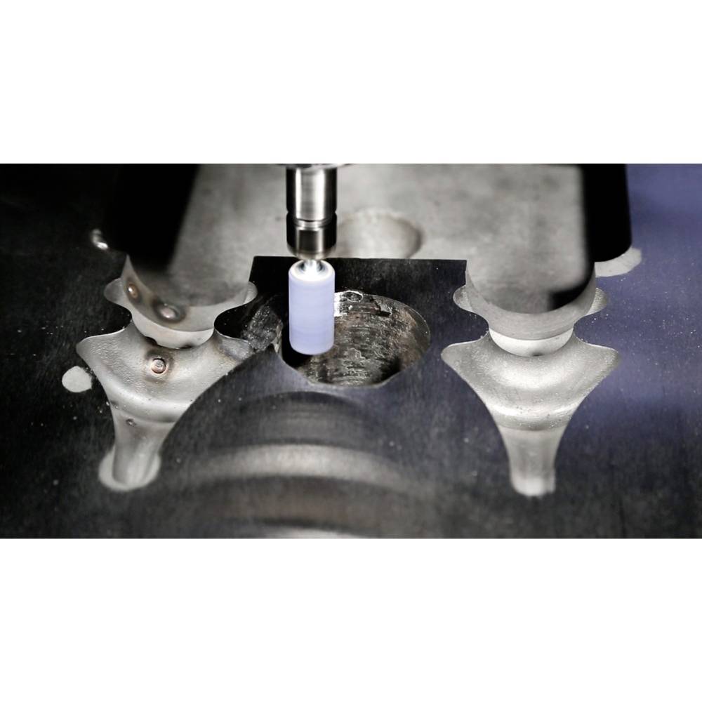 Maszyna obrabia element metalowy obrotowym wiertłem; przemysłowe środowisko produkcyjne.