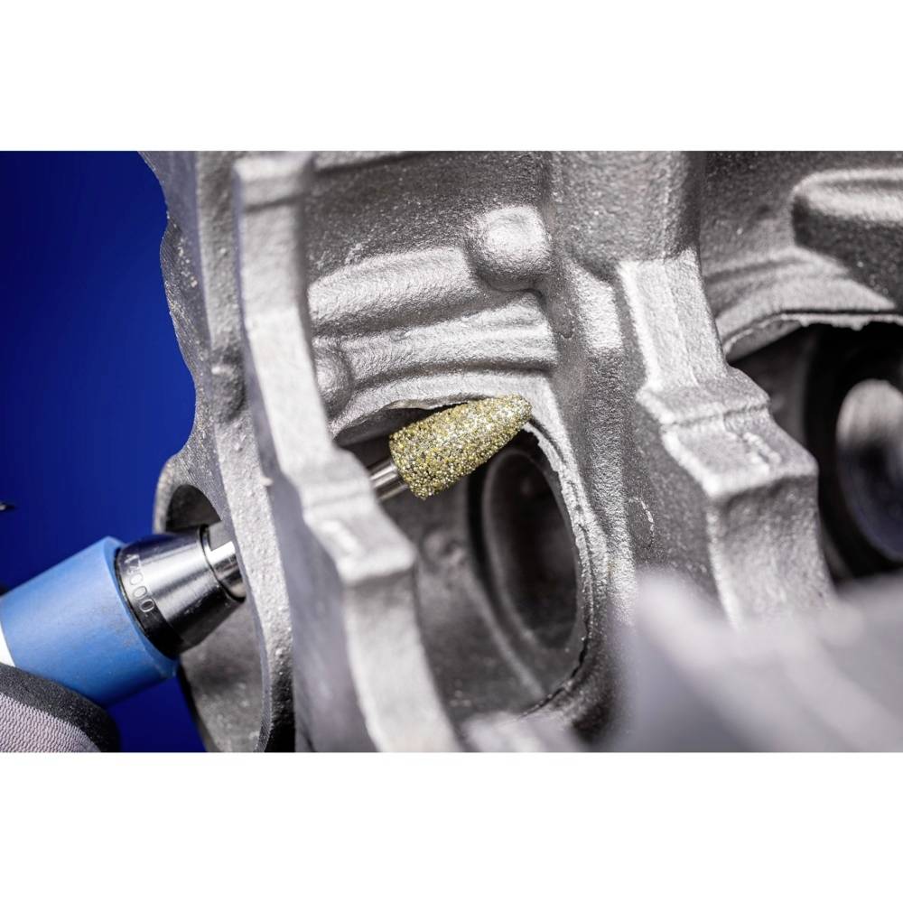 Zbliżenie elektrycznego narzędzia z nakładką szlifierską, obrabiającego element metalowy. Po lewej stronie widoczne jest urządzenie wiertnicze.