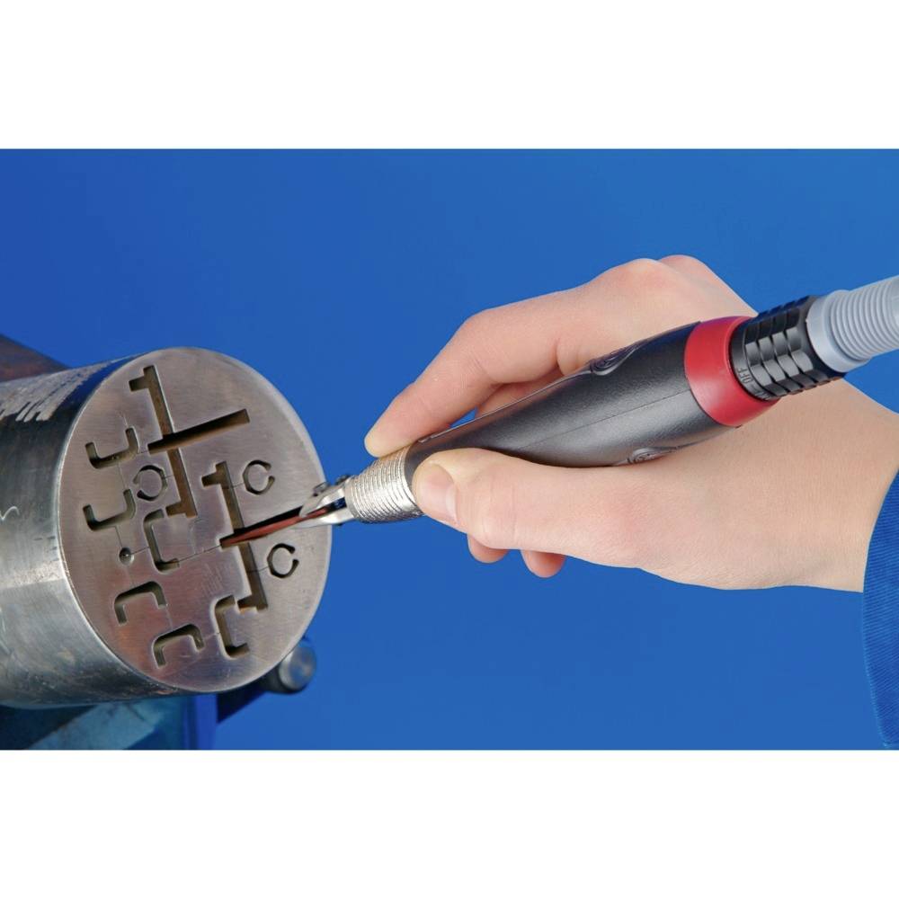 Dłoń trzyma narzędzie i graweruje cylindryczny kawałek metalu symbolami.