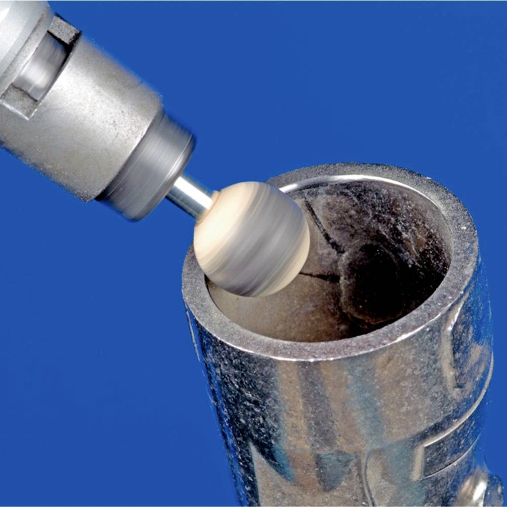 Wiertło obrabia okrągły kawałek metalu zamocowany w cylindrycznym uchwycie. Tło jest całkowicie niebieskie.