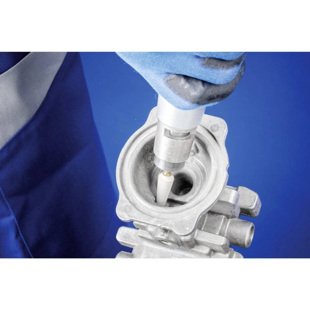 'Osoba czyści część maszyny za pomocą specjalnego narzędzia.'