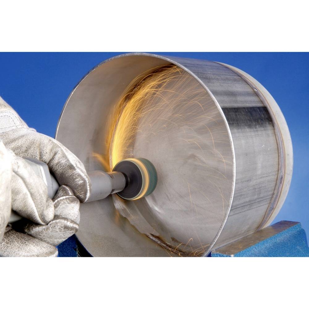 Osoba szlifuje wewnętrzną stronę metalowej rury elektronarzędziem, lecąc iskry. Nosi odzież ochronną.