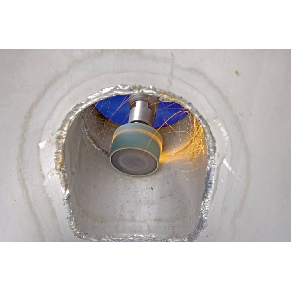 Maszyna szlifuje metal w rurze, lecą iskry.