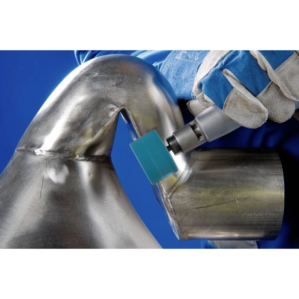 Osoba w niebieskich rękawiczkach szlifuje metalową rurę kątówką. Tło jest niebieskie.