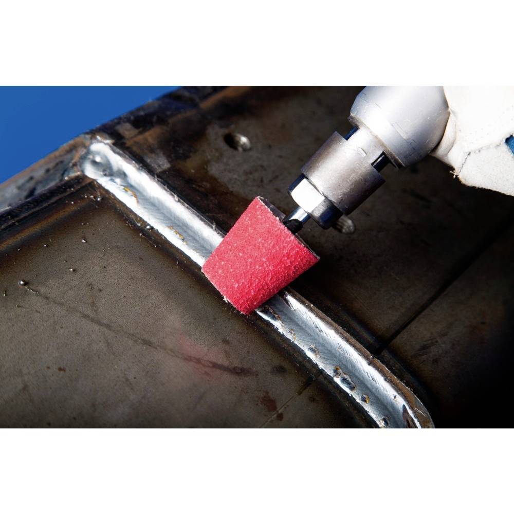 Obracające się narzędzie z czerwoną głowicą szlifierską poleruje spoinę na metalowej rurze. Proces obróbki metalu.