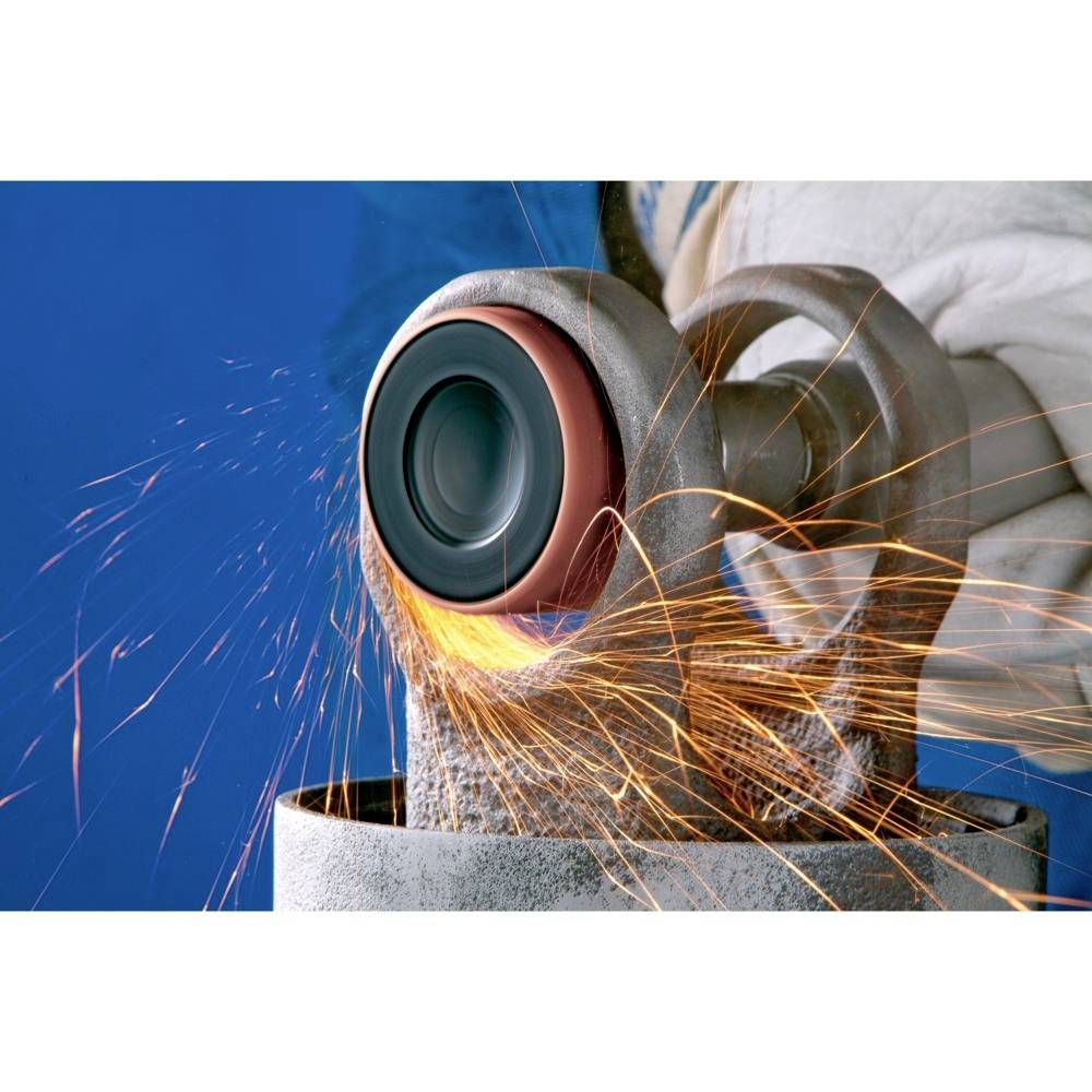 Osoba szlifuje metal za pomocą maszyny. Iskry lecą we wszystkich kierunkach. Obraz przedstawia rzemieślniczą pracę.