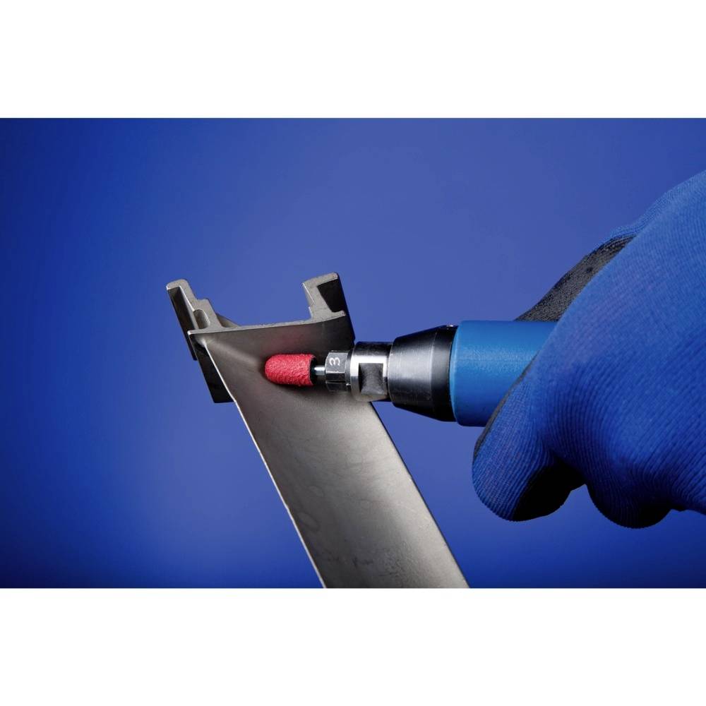 Dłoń w niebieskiej rękawicy trzyma narzędzie szlifujące krawędzie kawałka metalu na niebieskim tle.