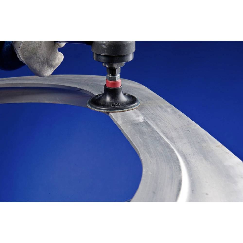 Ręka trzyma narzędzie ścierne, które obrabia powierzchnię metalową, aby ją wygładzić. Tło jest niebieskie.