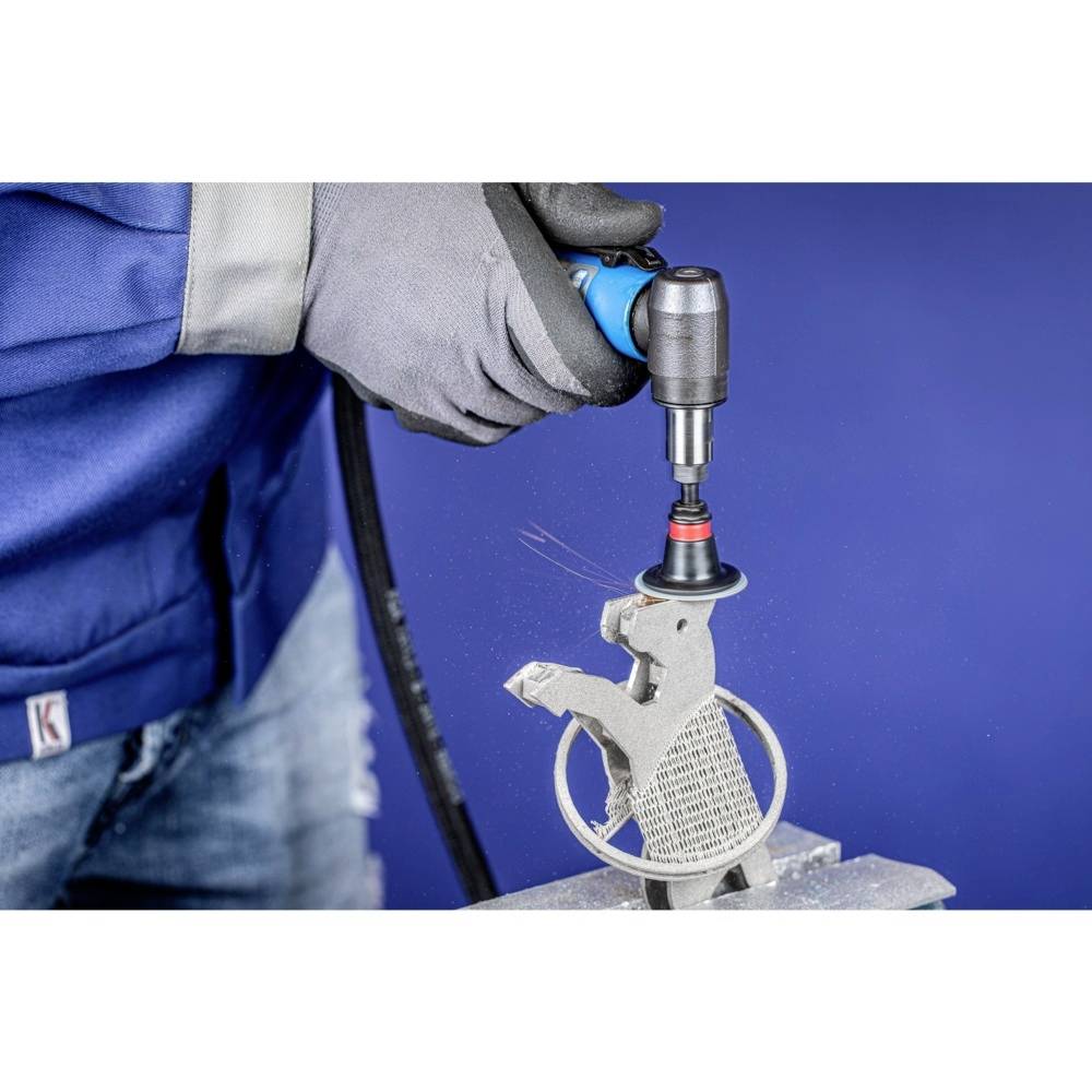 Osoba szlifuje metalową powierzchnię za pomocą narzędzia obrotowego. Jest ubrana w rękawice robocze i ubranie robocze na niebieskim tle.