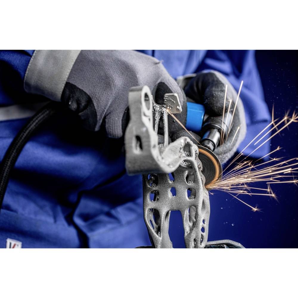 Osoba w odzieży ochronnej szlifuje metal szlifierką kątową. Obok obrabianego elementu lecą iskry.