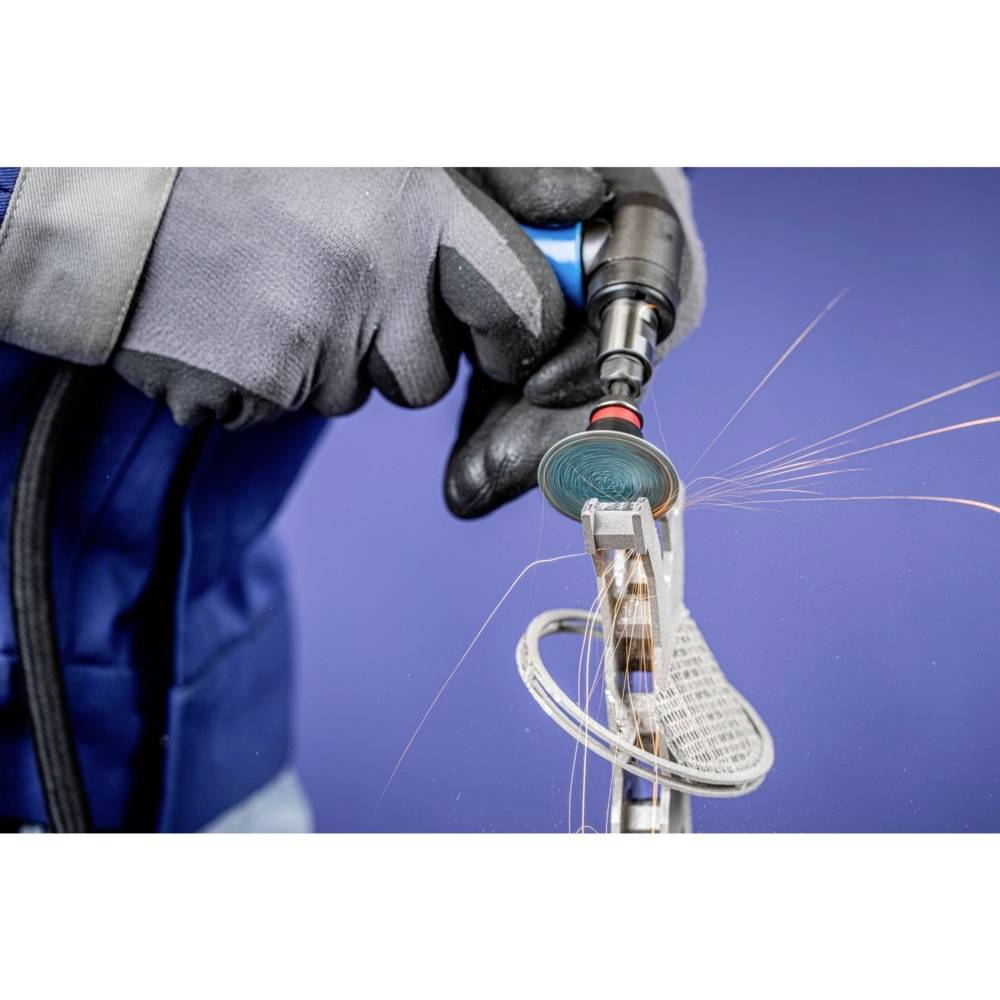 Osoba w rękawicach ochronnych szlifuje metal elektronarzędziem, podczas gdy lecą iskry.