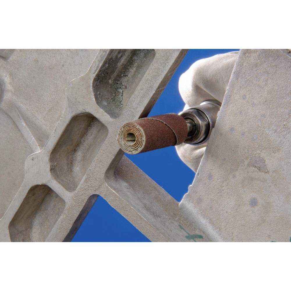 Dłoń trzyma szlifierkę wygładzającą metalową powierzchnię. Niebieskie tło dopełnia ujęcie.