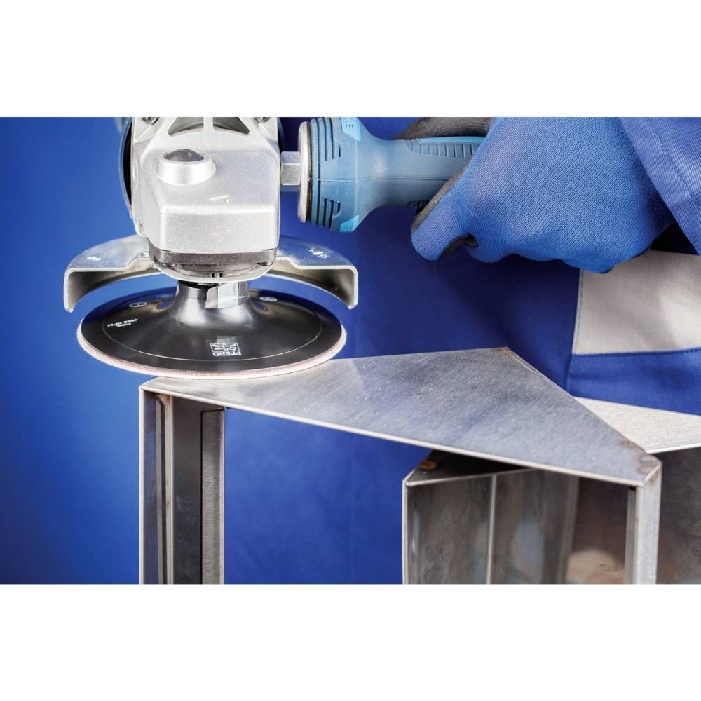 Osoba szlifuje krawędź metalową elektryczną szlifierką. Nosi niebieskie rękawice robocze.