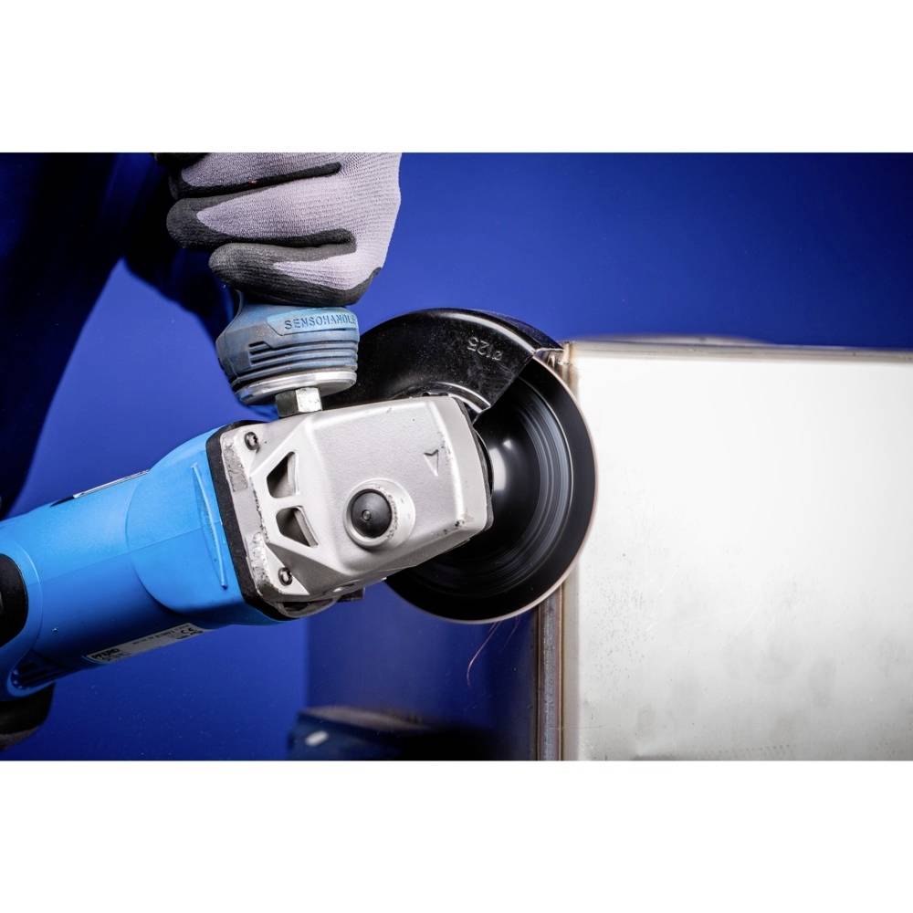 'Osoba w rękawicach szlifuje krawędź metalową elektronarzędziem. Niebieska powierzchnia w tle.'