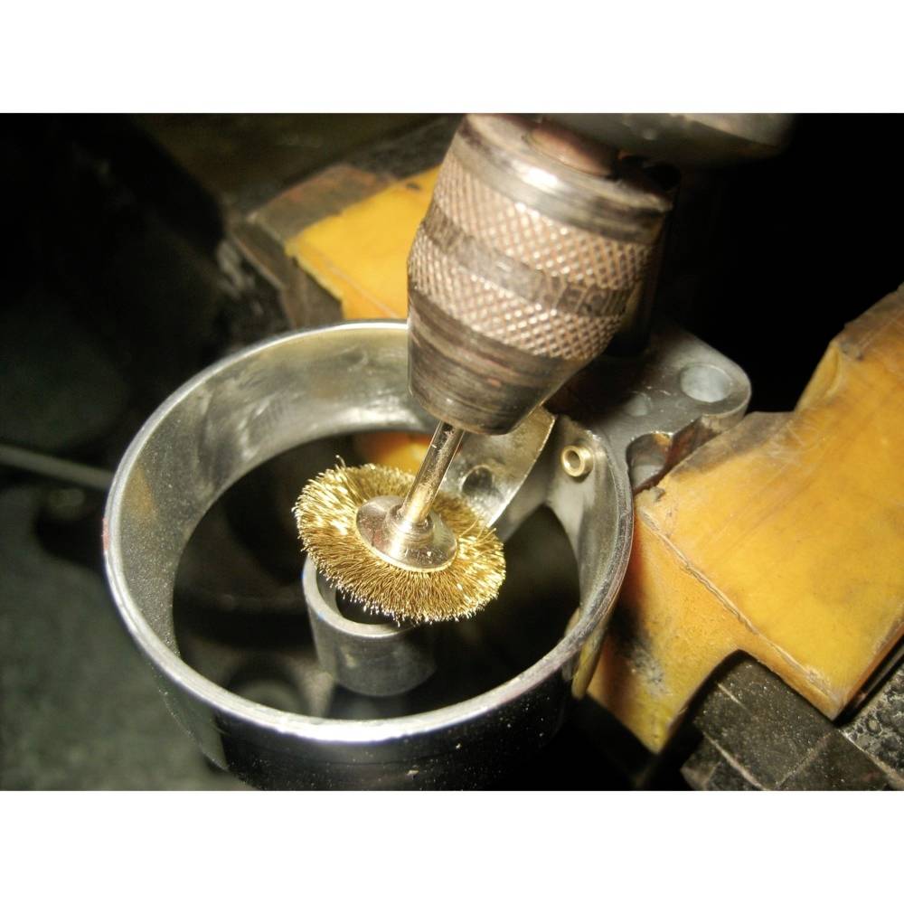 Szczotka druciana zamocowana w wiertarce czyszcząca metal; widok szczegółowy w środowisku warsztatu.