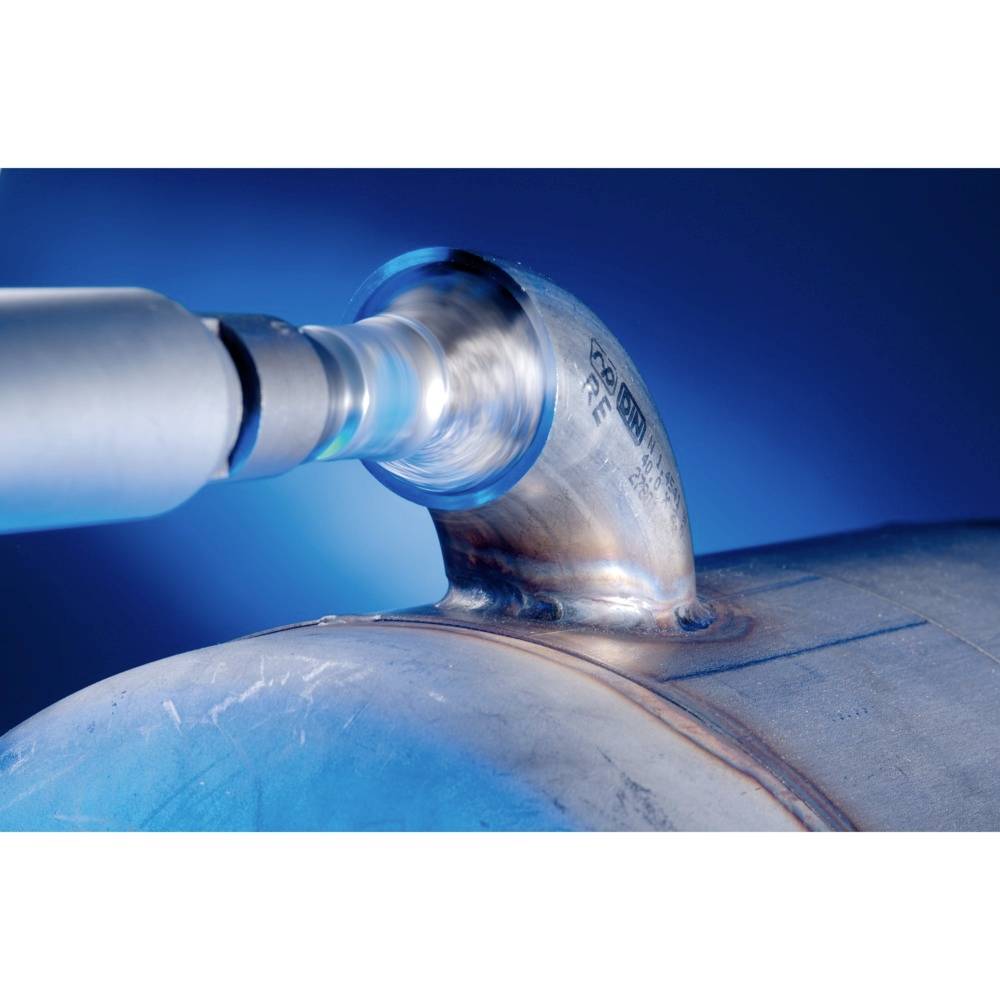 Narzędzie szlifierskie obrabia złącze metalowej rury. Tło jest niebieskie.