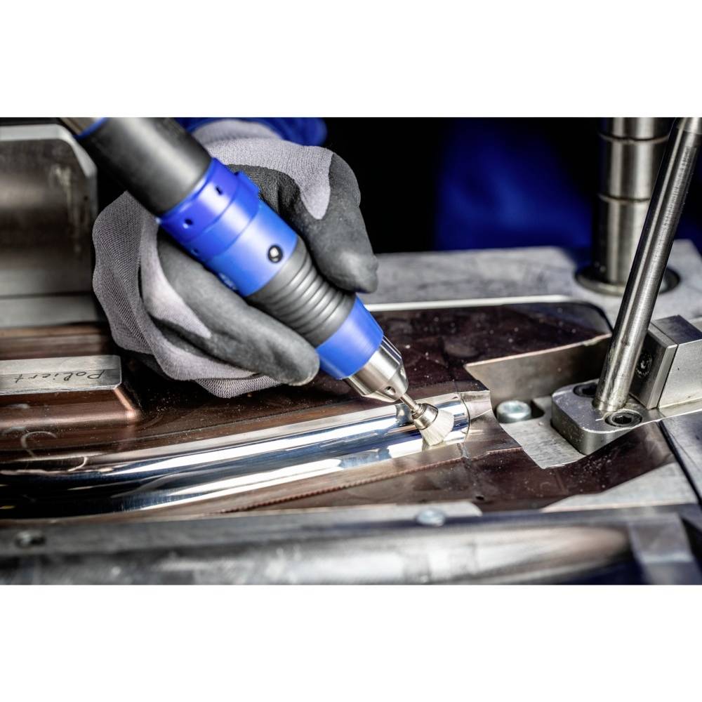 Osoba obrabia element metalowy niebieskim, ręcznym narzędziem elektrycznym. Rękawice zapewniają ochronę.