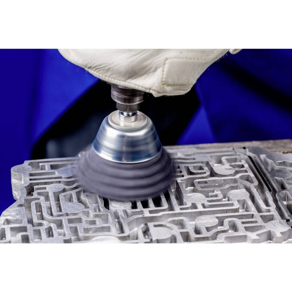 Osoba w rękawicy szlifuje skomplikowaną metalową część maszyną, przy czym lecą iskry.