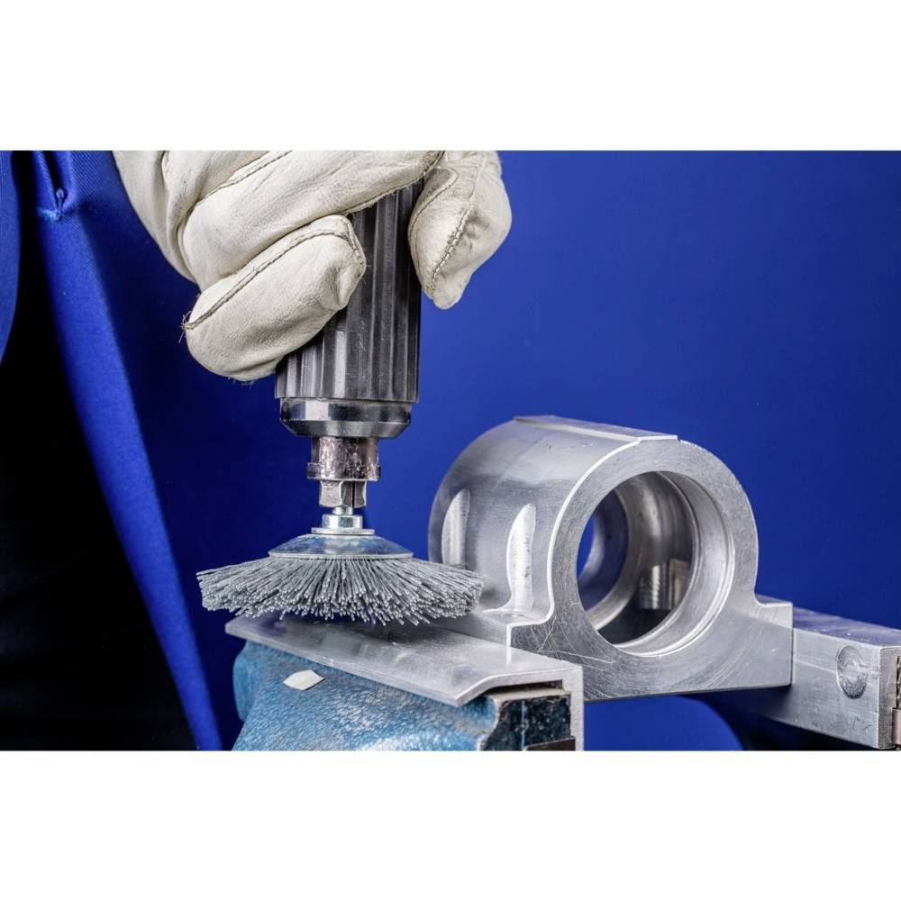 Ręcznie polerowana powierzchnia metalowa szczotką obrotową na niebieskim tle.