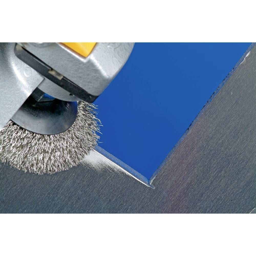 Szczotka druciana poleruje niebieski kątownik metalowy, wytwarzając iskry i nadając powierzchni gładkie, lśniące wykończenie.