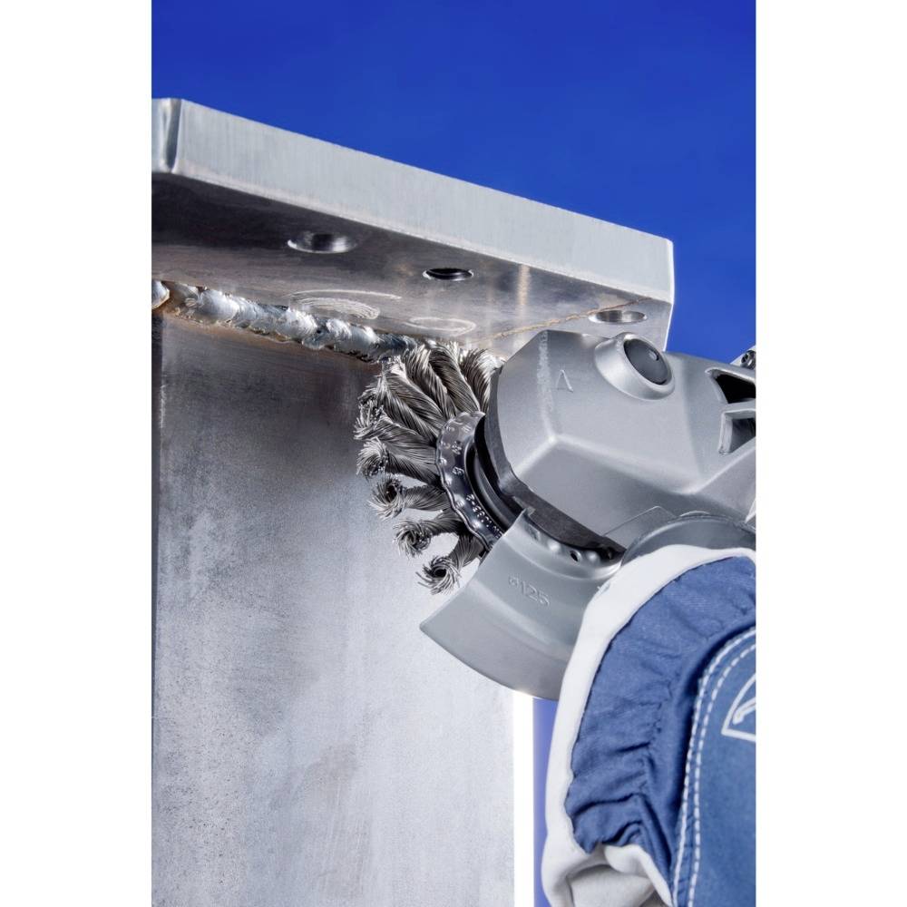 Osoba szlifuje spawane połączenie metalowe elektryczną szlifierką na dźwigarze I.