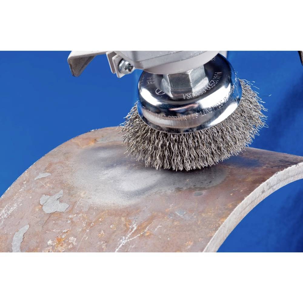 Maszynowa szczotka druciana czyści rdzewiejącą powierzchnię metalową. Zbliżenie ukazuje obracającą się szczotkę i usuwanie rdzy.