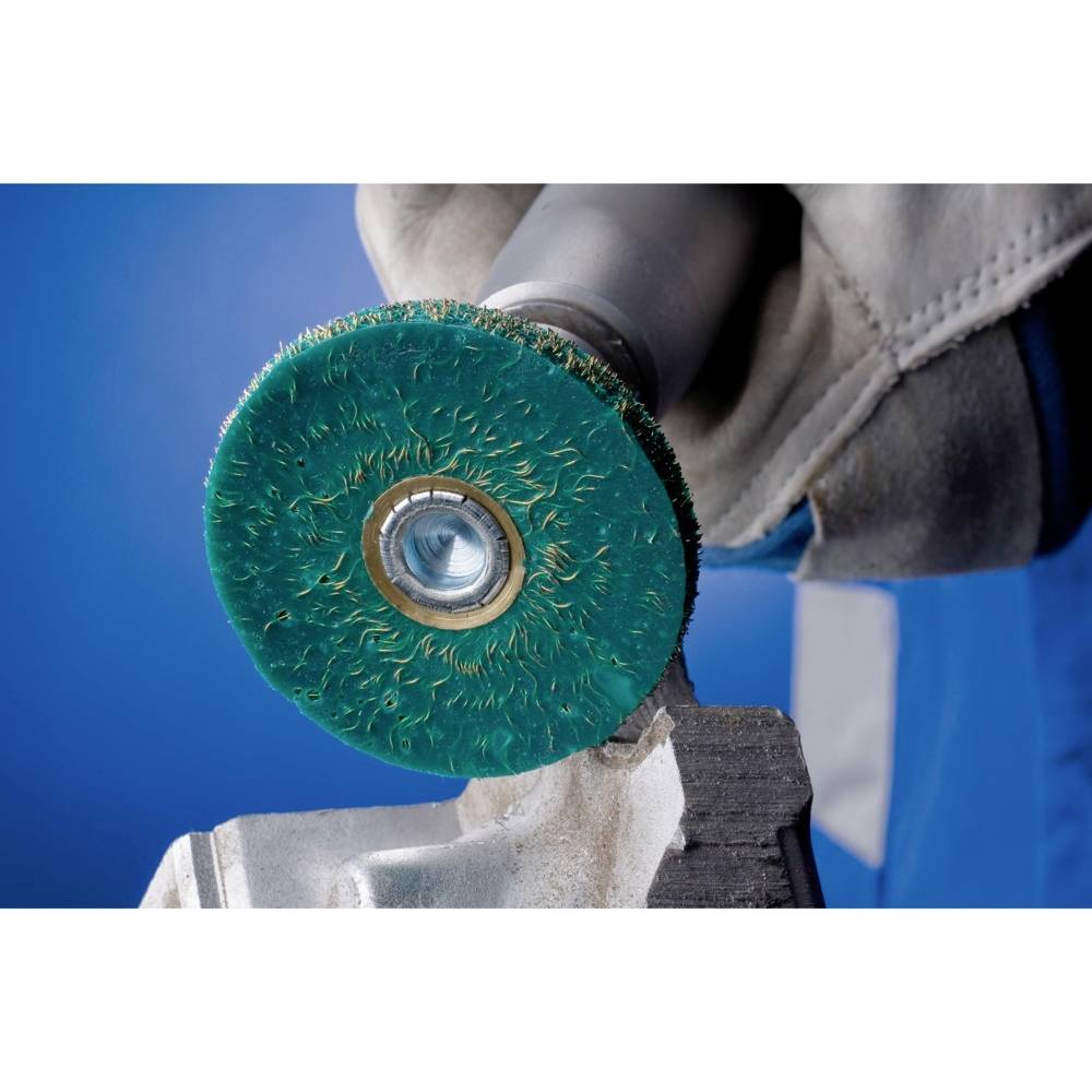 Zielona tarcza tnąca zamocowana w szlifierce kątowej służy do obróbki metalu. Dłoń w rękawicy mocno trzyma uchwyt.