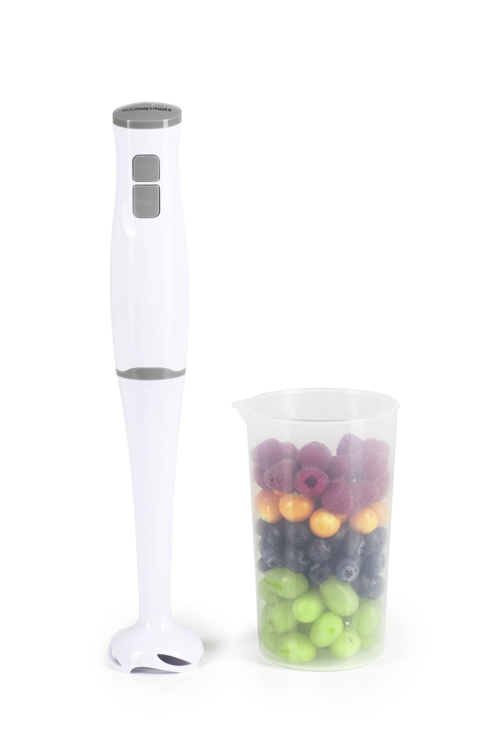 Biały blender stoi obok przezroczystego pojemnika wypełnionego kolorowymi owocami, takimi jak zielone jabłka, winogrona i maliny.