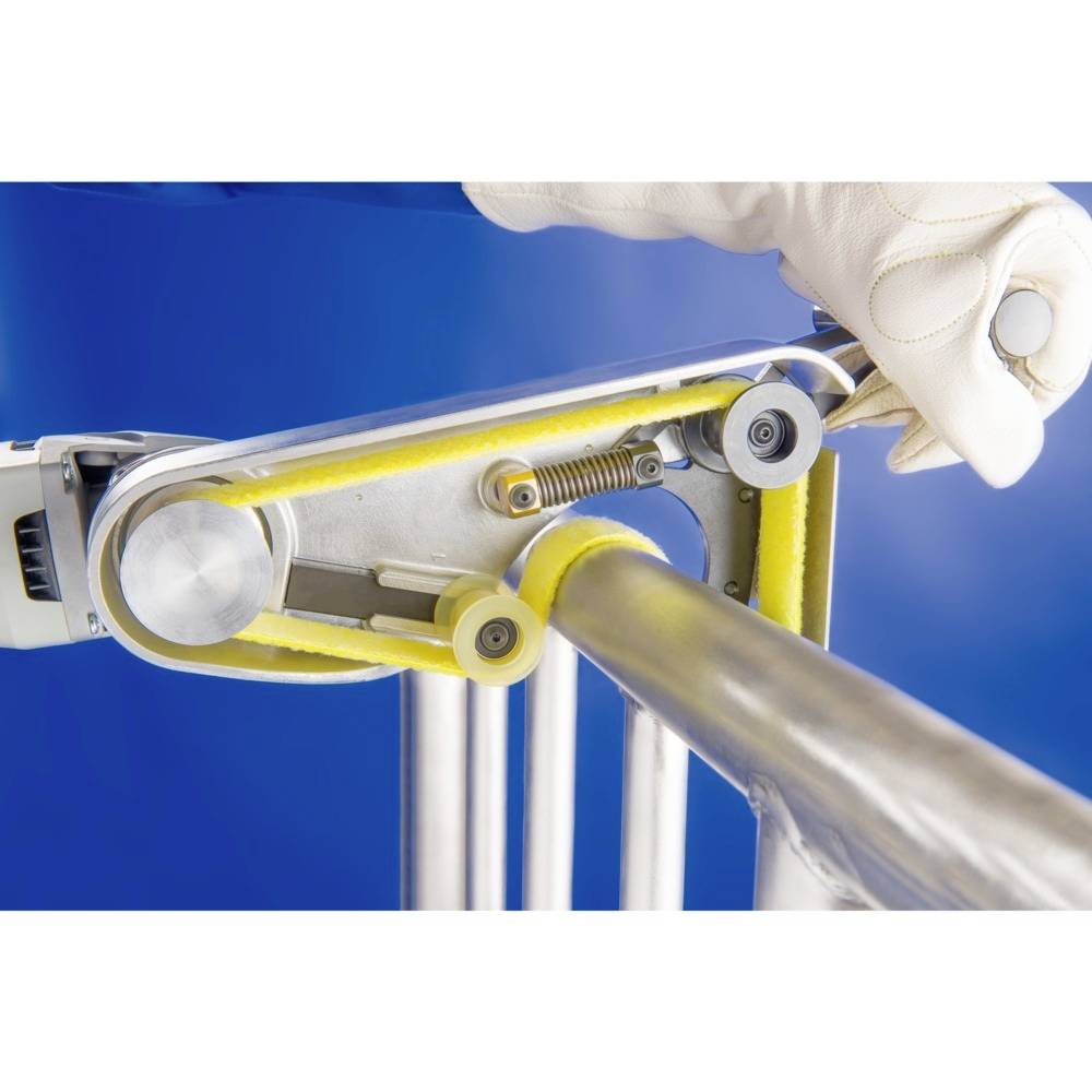 Szlifierka obrabia rurę metalową; ujęcie z bliska, fokus na taśmie ściernej i rękawicach; zastosowanie przemysłowe.