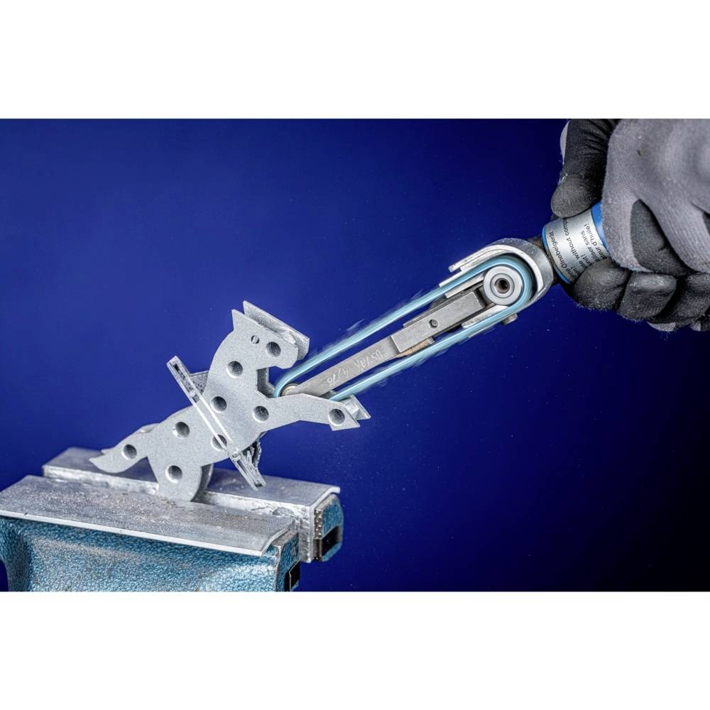 Ręka w rękawicy trzyma oscylujące narzędzie tnące, które przecina metal zaciśnięty w imadle, na niebieskim tle.