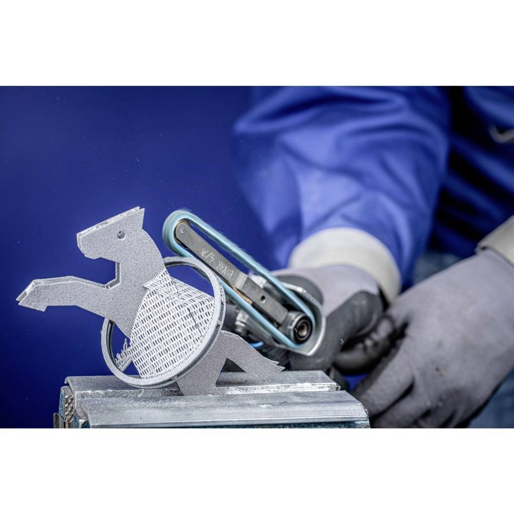 Osoba w rękawicach używa narzędzia szlifierskiego do obróbki metalowego elementu w kształcie konia.