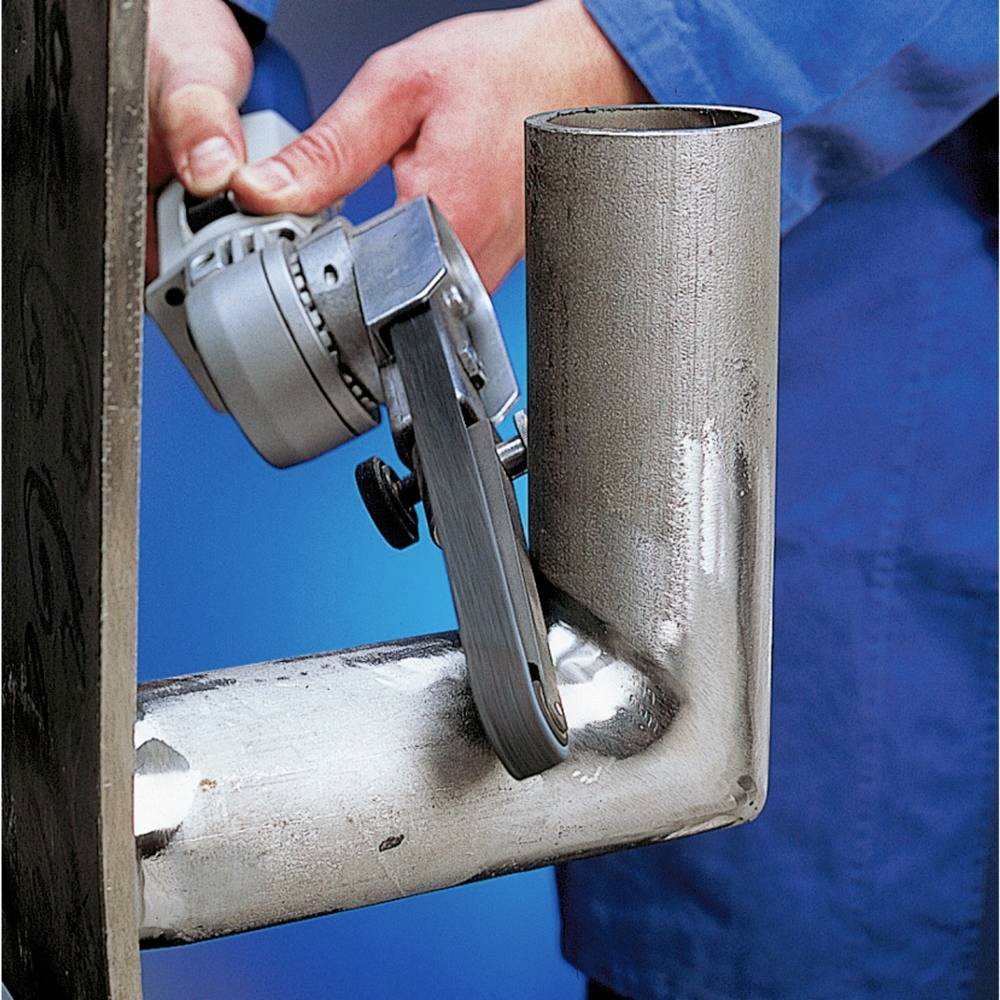 Osoba szlifuje krawędź metalowej rury elektryczną szlifierką, aby ją wygładzić, w środowisku warsztatu.