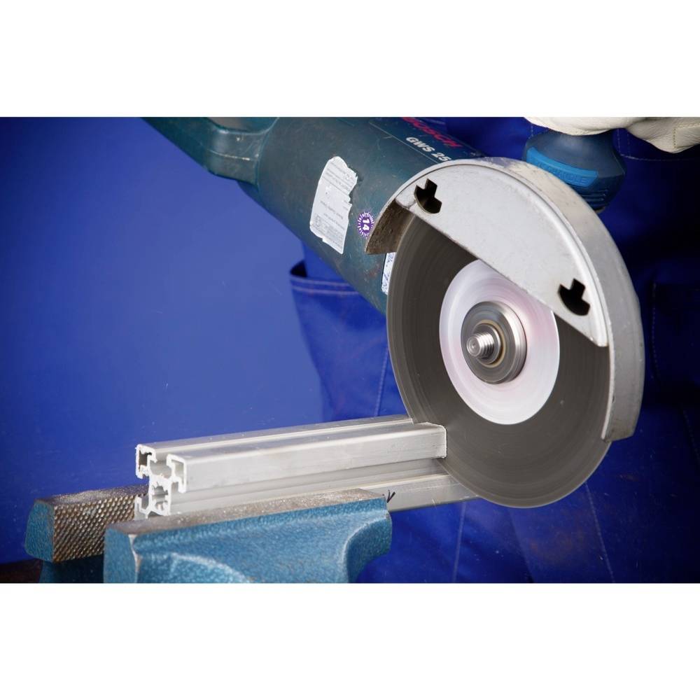 Piła tarczowa przecina profil aluminiowy. W tle widać rozmyte środowisko pracy.