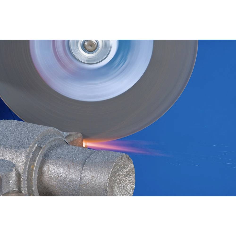 Obracająca się tarcza szlifierska obrabia kawałek metalu, podczas gdy na stanowisku przemysłowym pojawiają się iskry.