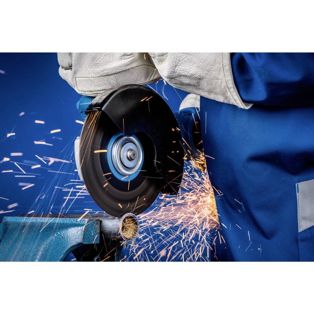 Osoba przecina metalową rurę elektryczną szlifierką, a wokół lecą iskry. Osoba jest ubrana w odzież ochronną.