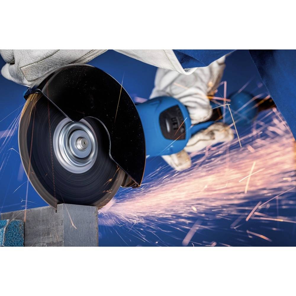 Robotnik w rękawicach ochronnych przycina metal szlifierką kątową, a iskry rozświetlają niebieskie tło.