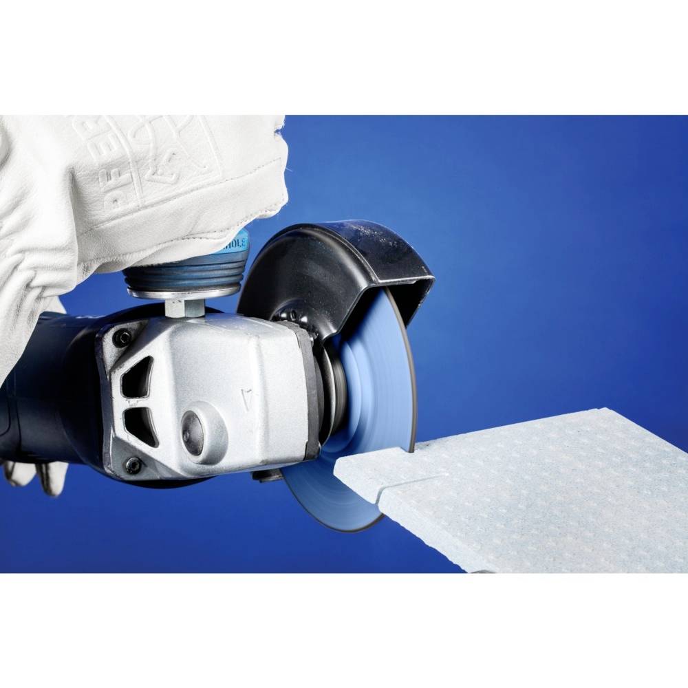 Zbliżenie tarczy tnącej wykonanej z metalu, która przecina cienką blachę. Dłoń w rękawicy bezpiecznie trzyma urządzenie.