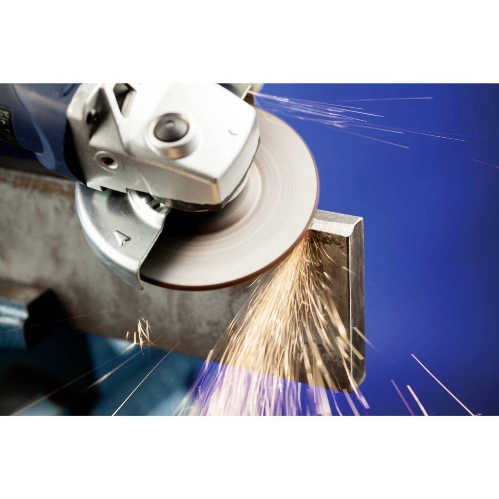 Szlifierka obrabia krawędź metalu, podczas gdy iskry lecą. Tło jest rozmyte i niebieskie.