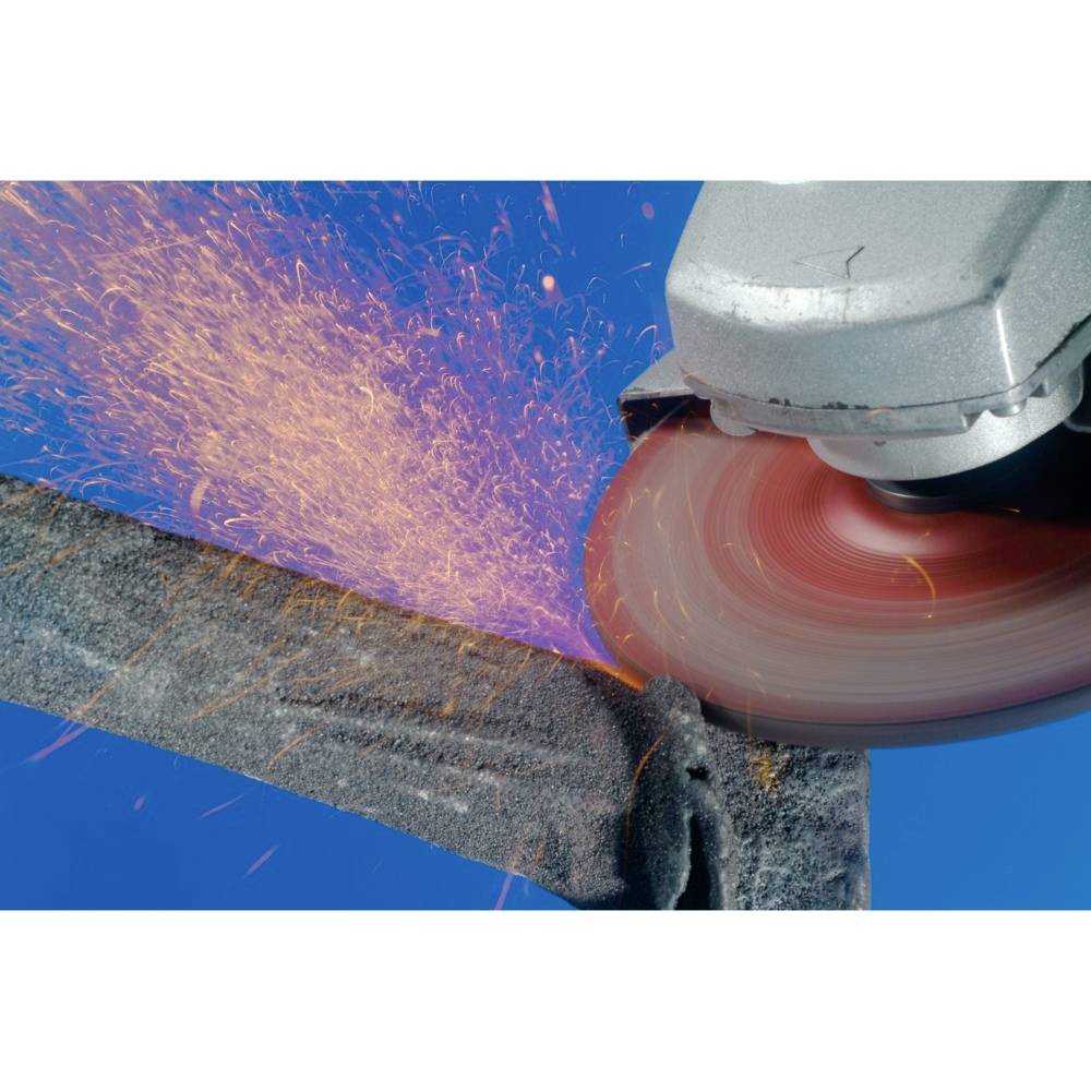 Szlifierka kątowa wytwarza iskry podczas szlifowania kawałka metalu. Deszcz iskier wyraźnie kontrastuje z niebieskim tłem.