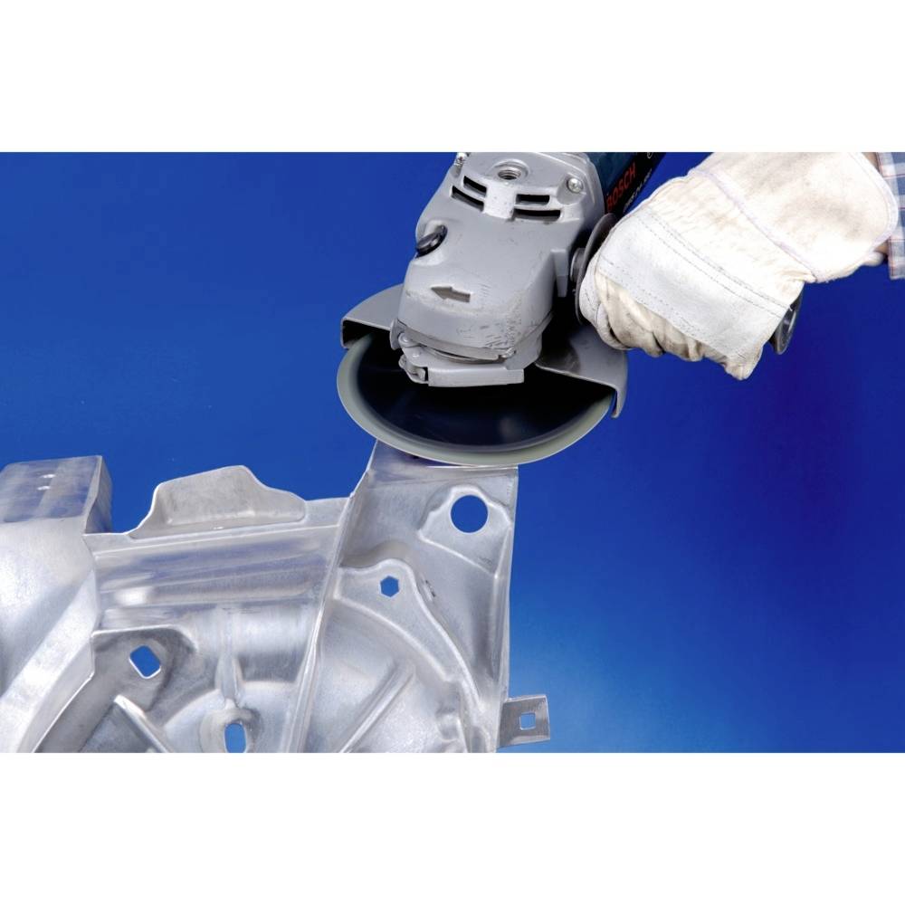 Osoba używa szlifierki do obróbki części metalowej. Ręka jest zabezpieczona rękawicą ochronną, a tło jest niebieskie.